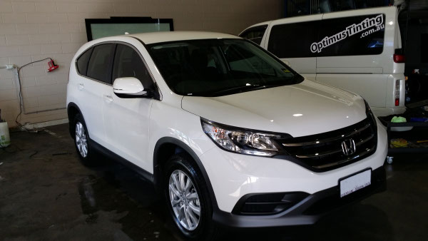 car window tint installation on a white colour Honda CR-V automobile front view