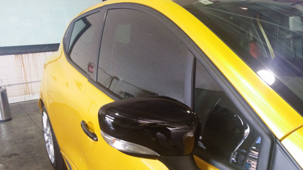 close up side view of car window tinting completed on yellow colour Renault Clio