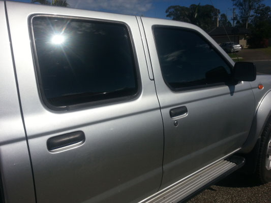 close up side view of grey colour Nissan Navara Ute after car windows tinted